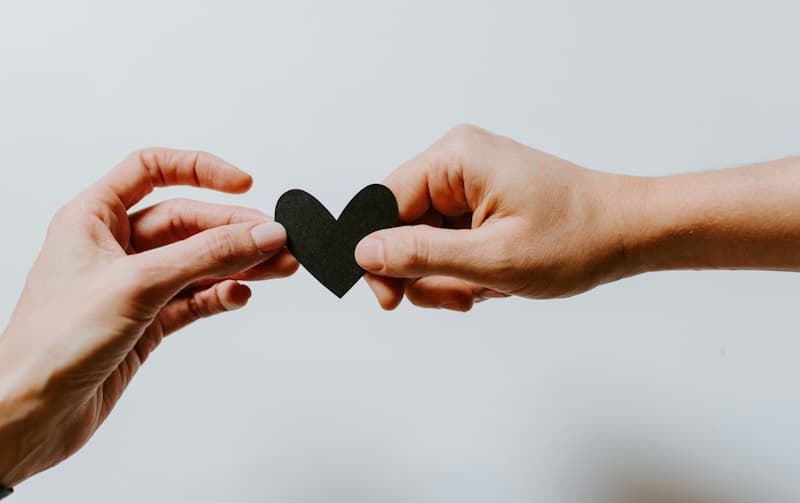 Two people holding a paper-cut heart